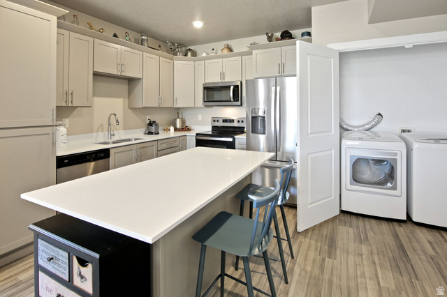 2101 North Main Street, Unit 306 Sunset, UT 84015 - Photo 6 of 22 Kitchen featuring an island with white countertop, stainless steel appliances, light-toned cabinetry, and wood-finish flooring