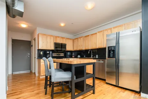 a kitchen with stainless steel appliances a refrigerator a stove a dining table and chairs with wooden floor