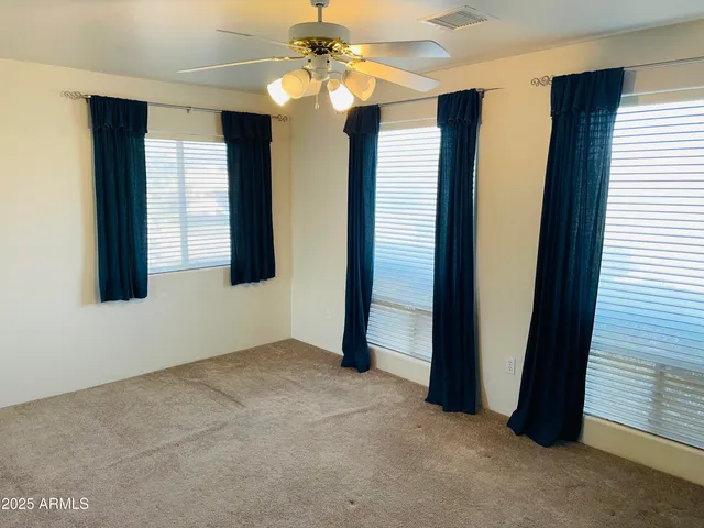 an empty room with windows and fan