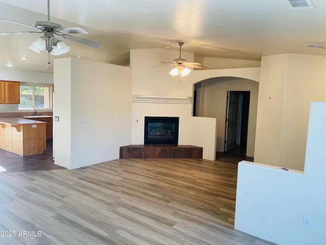 a view of an empty room with a fireplace and a kitchen view