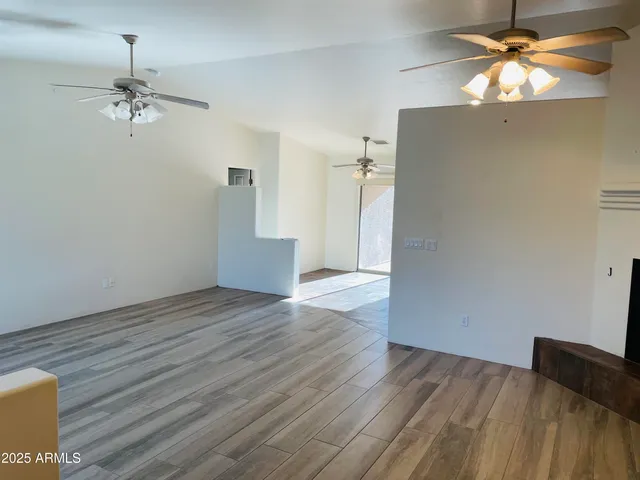 a view of empty room with wooden floor and fan