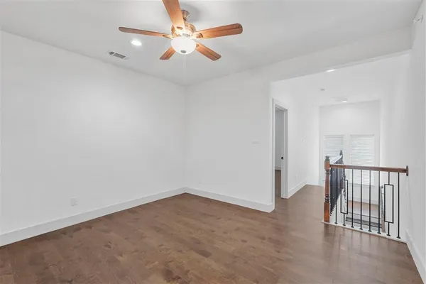 an empty room with wooden floor and fan