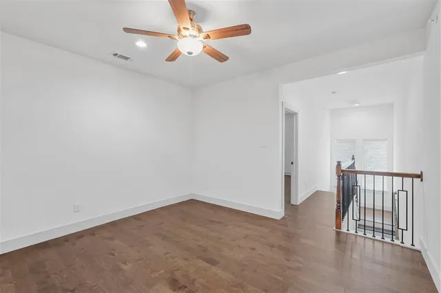 an empty room with wooden floor and fan