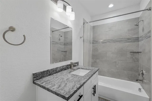 a bathroom with a granite countertop bathtub shower sink and mirror