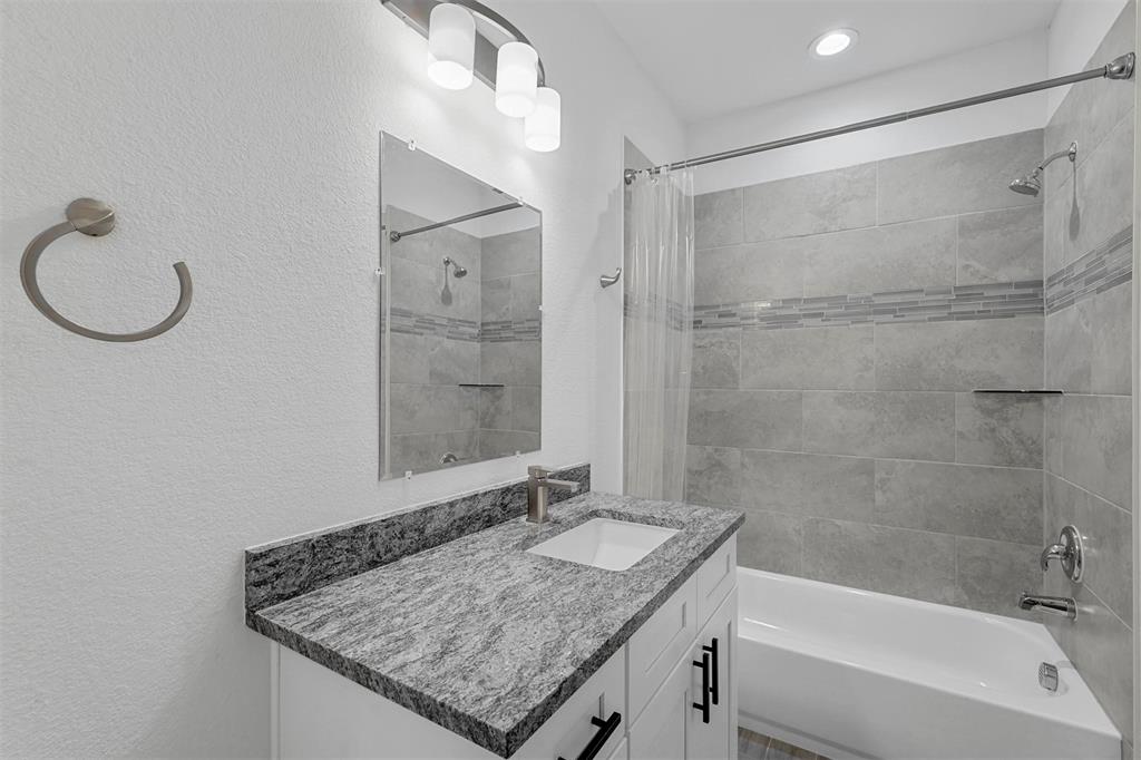 6059 Rivendell Drive Frisco, TX 75035 - Photo 17 of 30 a bathroom with a granite countertop bathtub shower sink and mirror