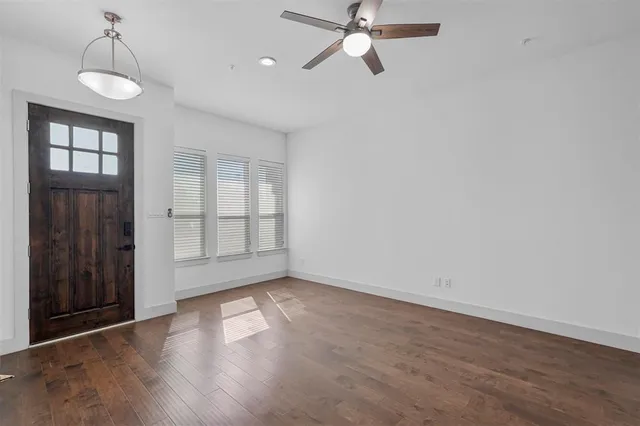 an empty room with wooden floor fan and windows