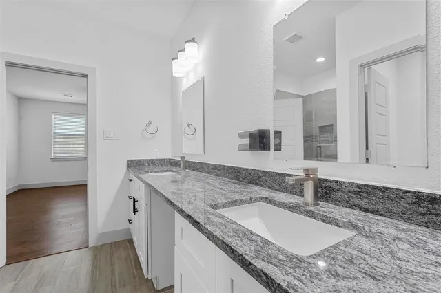 a bathroom with a granite countertop double vanity sink and a mirror
