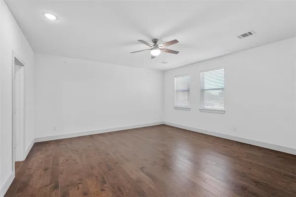 an empty room with wooden floor and ceiling fan