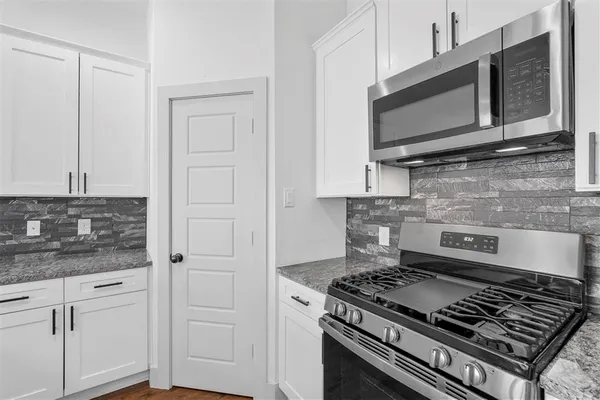 a kitchen with stainless steel appliances granite countertop white cabinets and black stove top oven with granite countertops