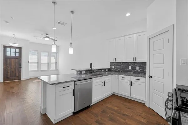 a kitchen with stainless steel appliances granite countertop a sink and dishwasher with white cabinets
