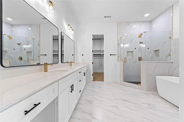 a bathroom with a double vanity sink a large mirror a shower and a bathtub