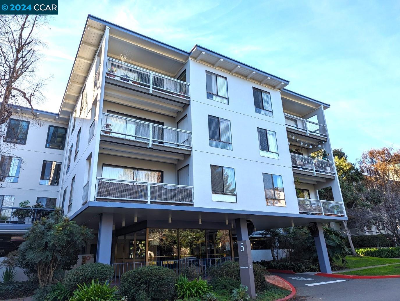 5 Commodore Drive, Unit B202 Emeryville, CA 94608 - Photo 1 of 1 a front view of a building with balcony and trees