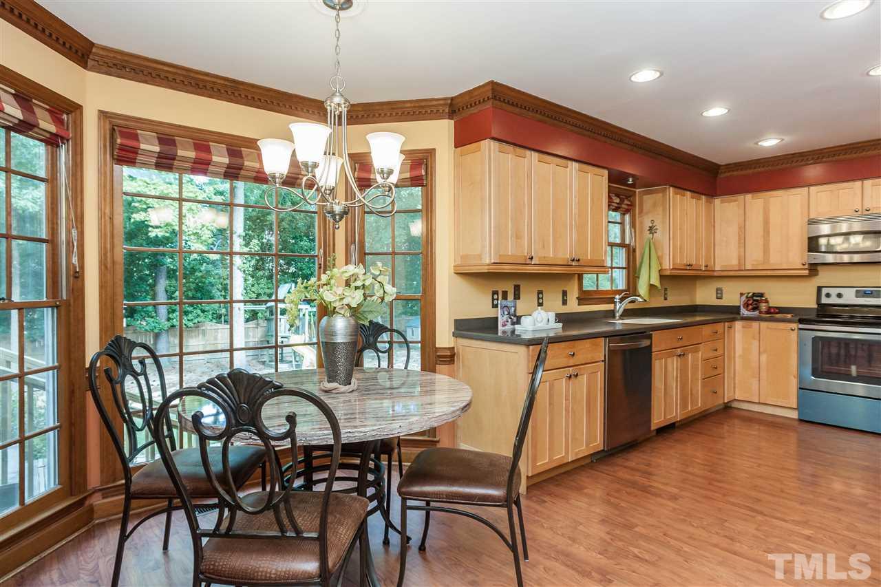 7205 Sawbuck Court Raleigh, NC 27613 - Photo 9 of 25 a kitchen with stainless steel appliances granite countertop wooden floor dining table and chairs