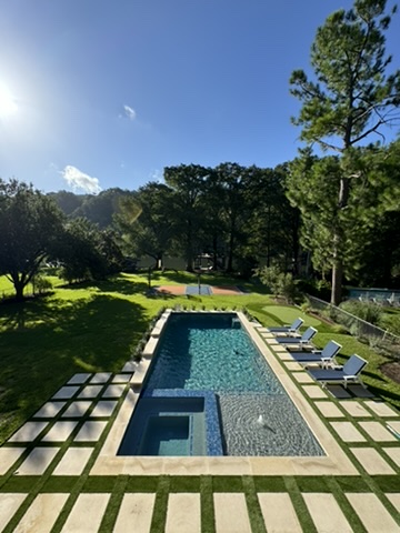 View of swimming pool with a pool with connected hot tub, a patio, and view of wooded area