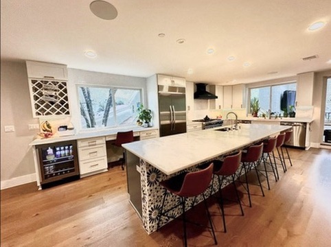 2007 Manana Street Austin, TX 78730 - Photo 34 of 38 Kitchen featuring beverage cooler, a breakfast bar area, white cabinetry, a spacious island, and light wood-type flooring