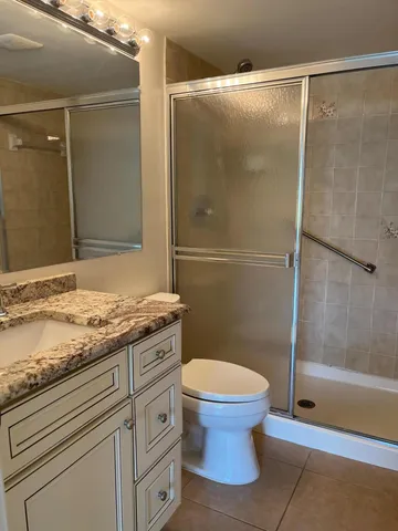 a bathroom with a granite countertop sink toilet and shower