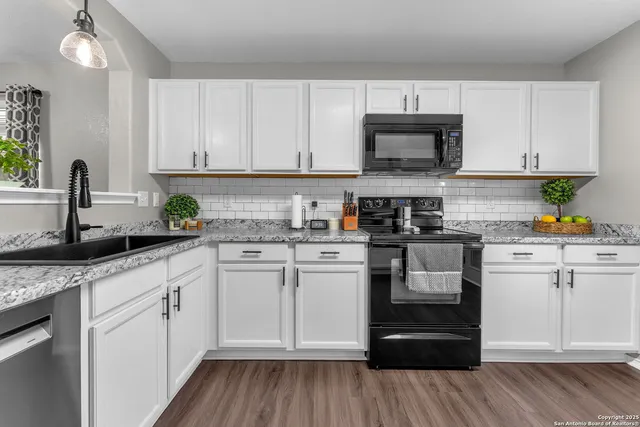 a kitchen with stainless steel appliances granite countertop a stove a sink and white cabinets