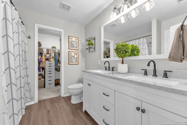 a bathroom with a granite countertop sink vanity mirror and toilet