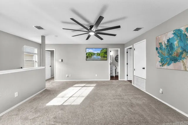 a view of a livingroom with a ceiling fan & windows