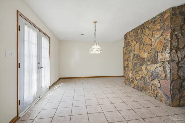an empty room with windows and chandelier fan