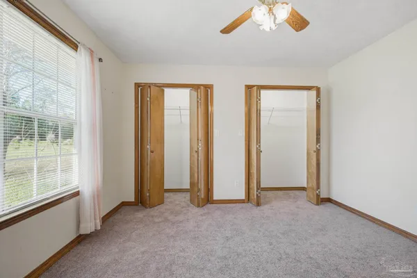 an empty room with a window and a fan