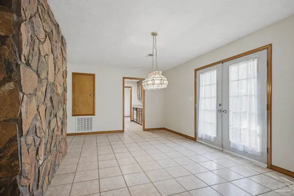 a view of an empty room with window and chandelier fan