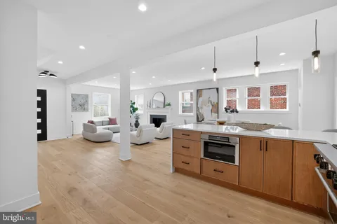 a large white kitchen with stainless steel appliances granite countertop a lot of cabinets and wooden floor