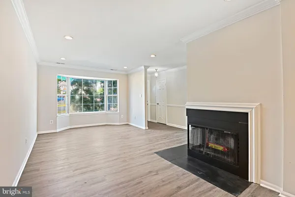 an empty room with wooden floor fireplace and windows