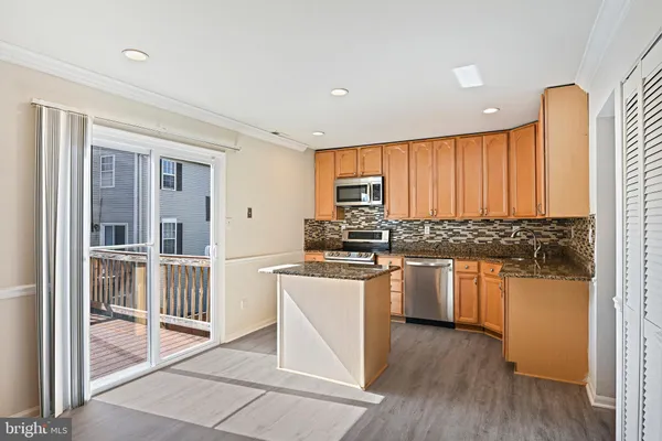 a kitchen with stainless steel appliances granite countertop white cabinets a refrigerator a stove a sink and dishwasher with wooden floor