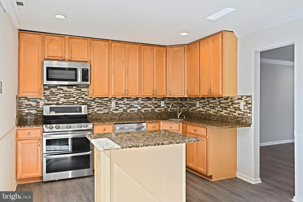 a kitchen with granite countertop wooden cabinets and stainless steel appliances