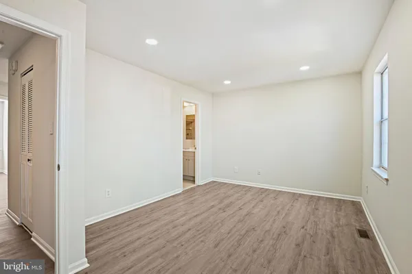 a view of an empty room with wooden floor and closet
