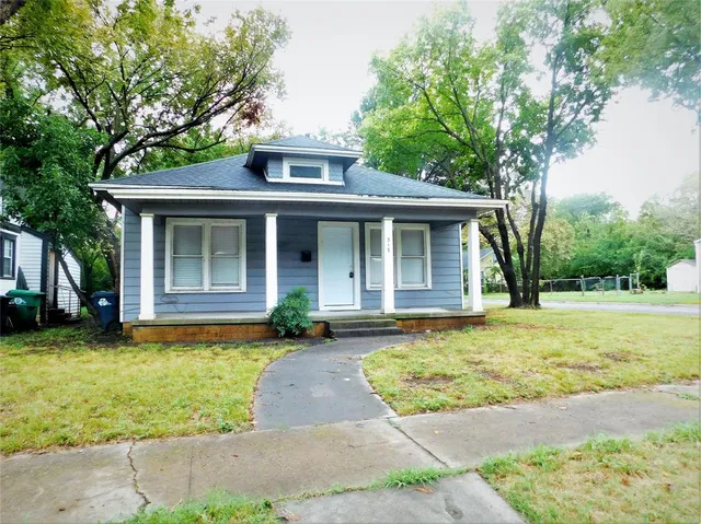 a front view of a house with a garden and trees