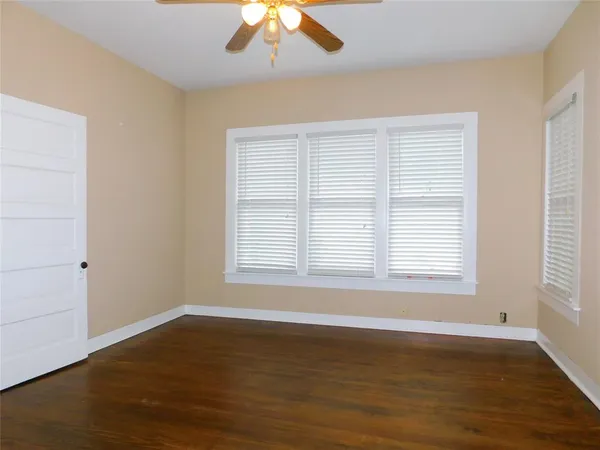 an empty room with wooden floor fan and window