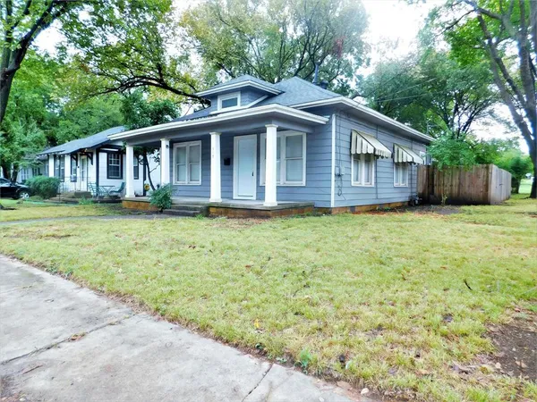 a view of a house with a yard and large trees