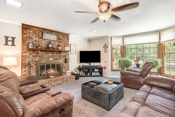 a living room with furniture a flat screen tv and a large window