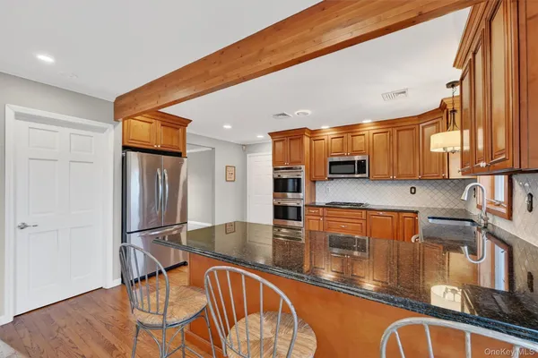 a kitchen with stainless steel appliances granite countertop a refrigerator a stove and a sink with granite countertops
