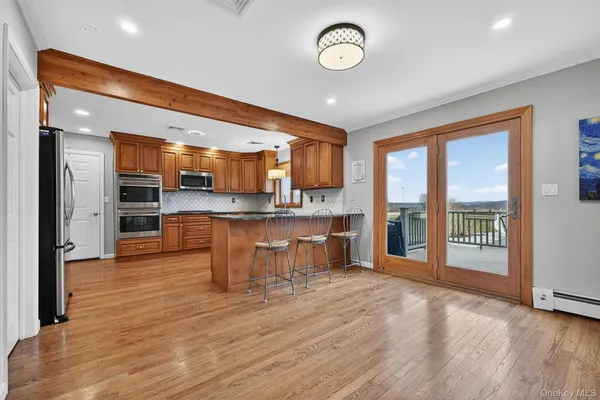 an open kitchen with kitchen island wooden floor and stainless steel appliances
