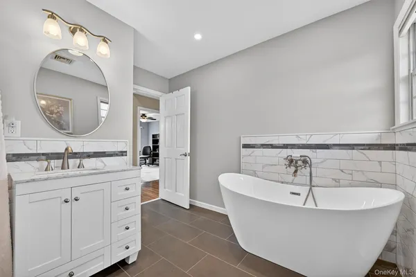a spacious bathroom with a double vanity sink mirror and bathtub