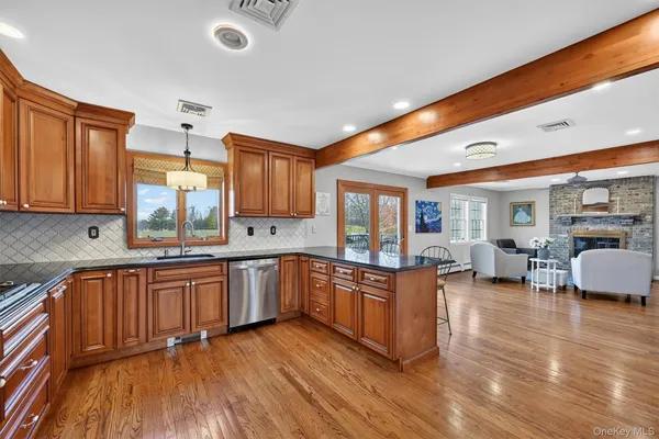 a large kitchen with stainless steel appliances granite countertop wooden floors and view of living room