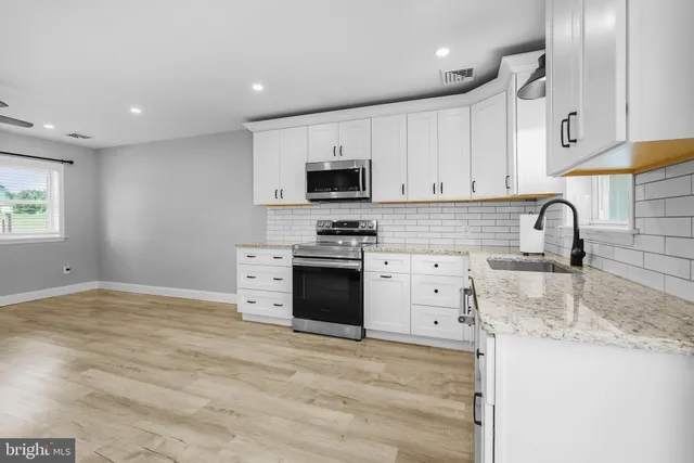a kitchen with granite countertop a stove a sink and a microwave