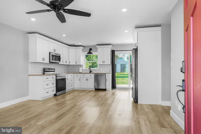 a kitchen with stainless steel appliances granite countertop a refrigerator a stove top oven a sink and dishwasher with wooden floor