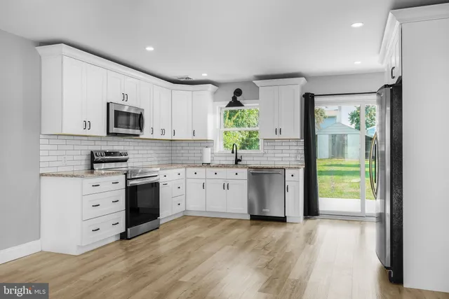 a kitchen with granite countertop a stove a sink and a microwave