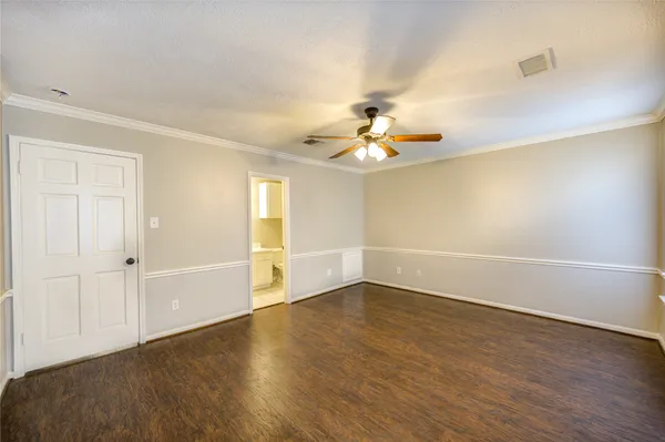 an empty room with wooden floor and chandelier fan