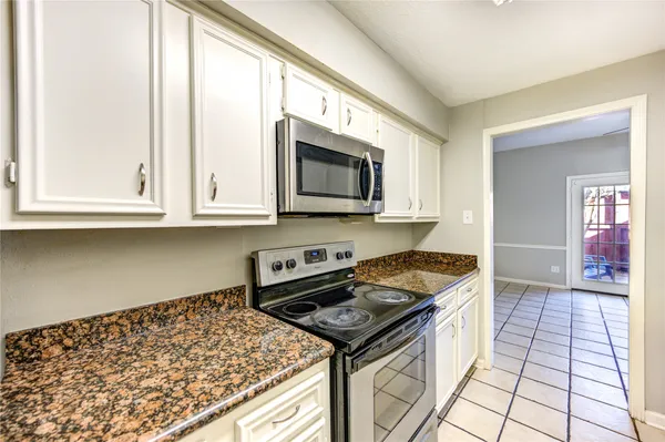 a kitchen with granite countertop a stove top oven microwave and cabinets