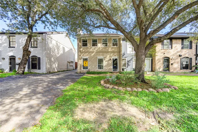 a view of a white house with a big yard and large tree