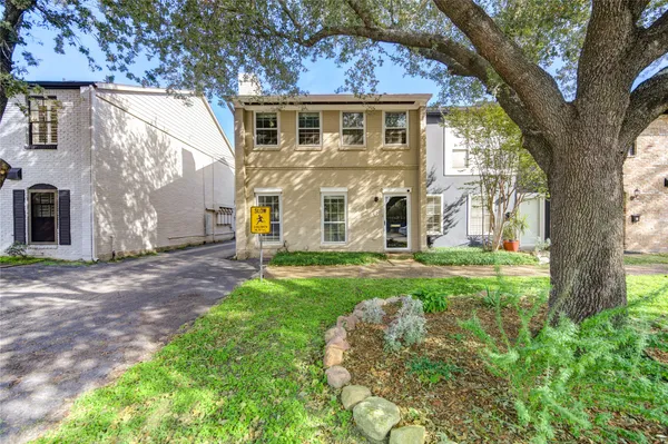 a view of a yard in front of a house with a large tree