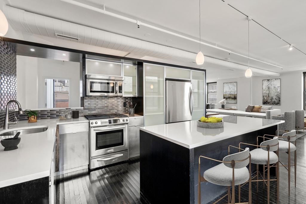 453 Washington Street, Unit 11B Boston, MA 02111 - Photo 8 of 30 a kitchen with a stove a sink a kitchen island with chairs and wooden floor