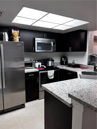 a kitchen with stainless steel appliances granite countertop a sink a stove and a refrigerator