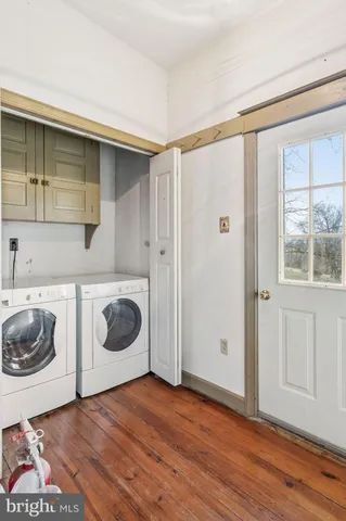 a utility room with wooden floor washer and dryer