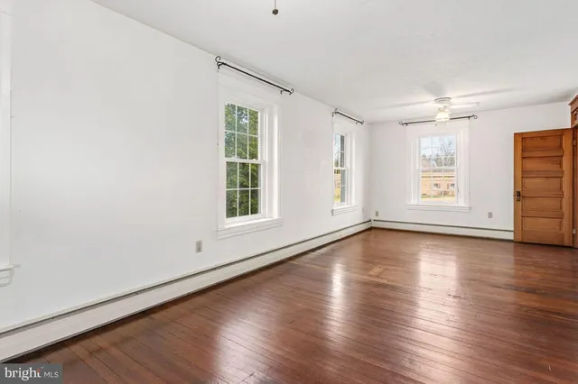 an empty room with wooden floor and windows